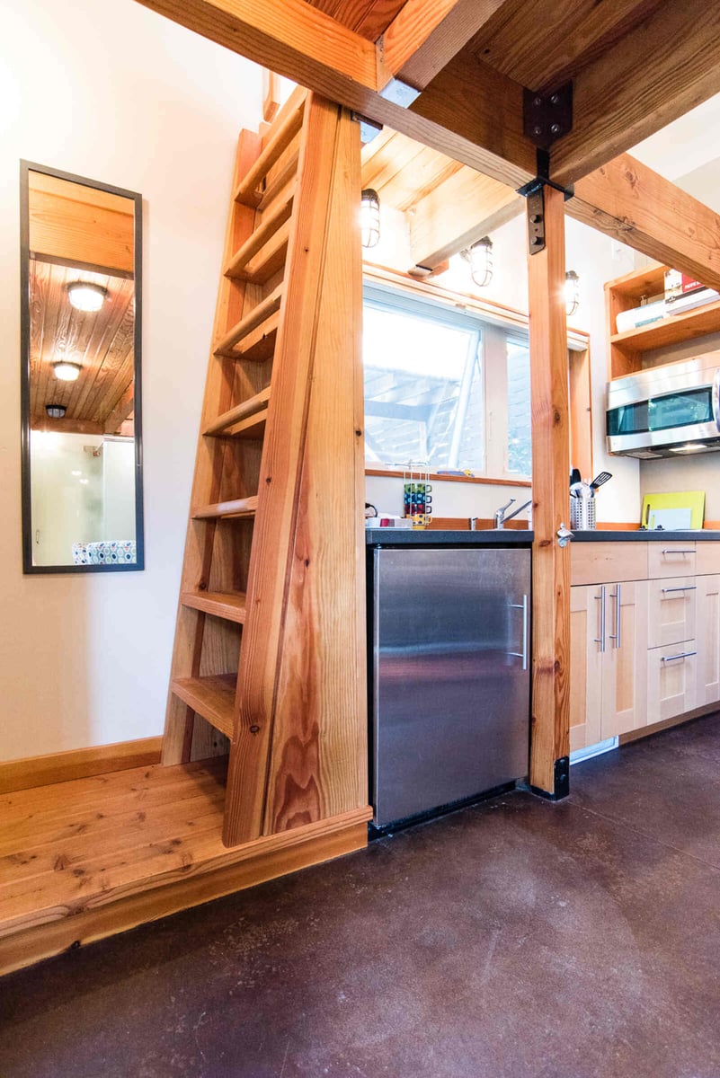 Interior view of an ADU kitchen with a wooden loft ladder and stainless steel appliances, remodeled by CB Construction in Seattle