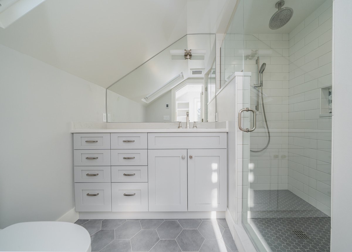 Bright bathroom with custom cabinetry and glass shower enclosure by CB Construction in Seattle