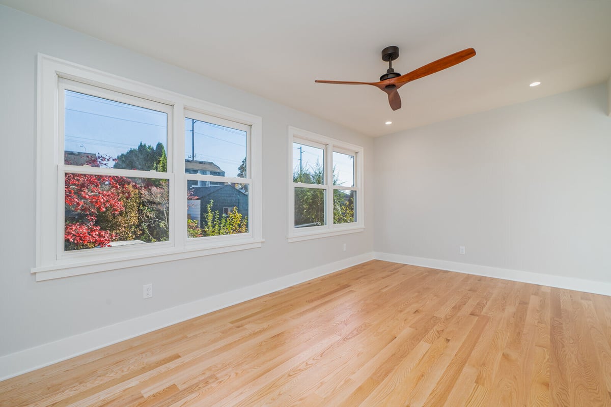 Bright bedroom with large windows and hardwood flooring in a Seattle home remodel by CB Construction