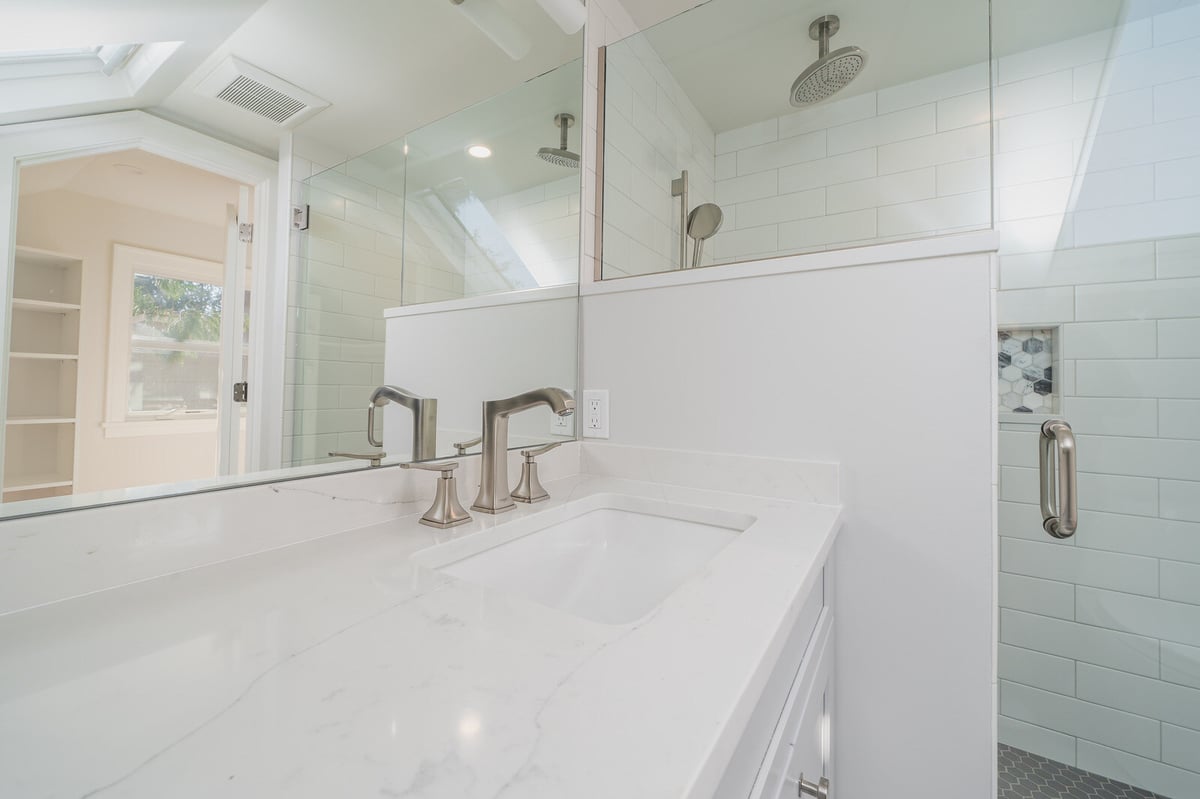 Close-up of a marble sink countertop and glass shower in a remodeled Seattle bathroom by CB Construction