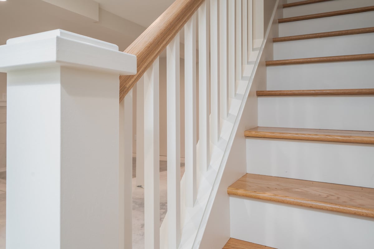 Close-up of a modern stairway with wooden handrails and white spindles in Seattle, by CB Construction