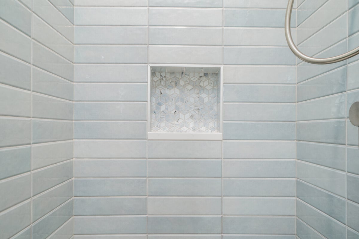 Close-up of a shower niche with geometric tiles in a remodeled Seattle bathroom by CB Construction