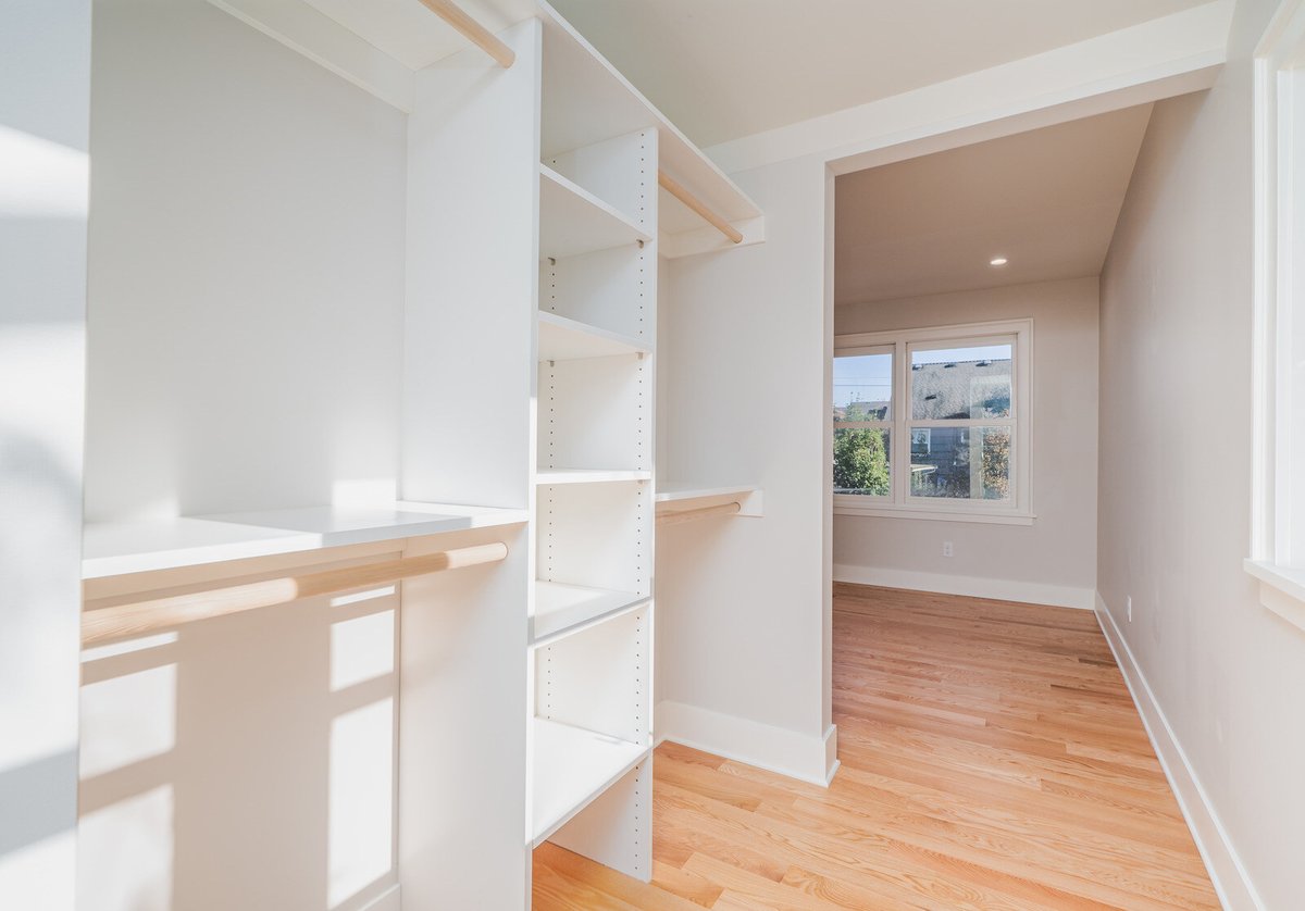 Custom-built closet space with white shelves and hardwood floors, remodeled by CB Construction in Seattle