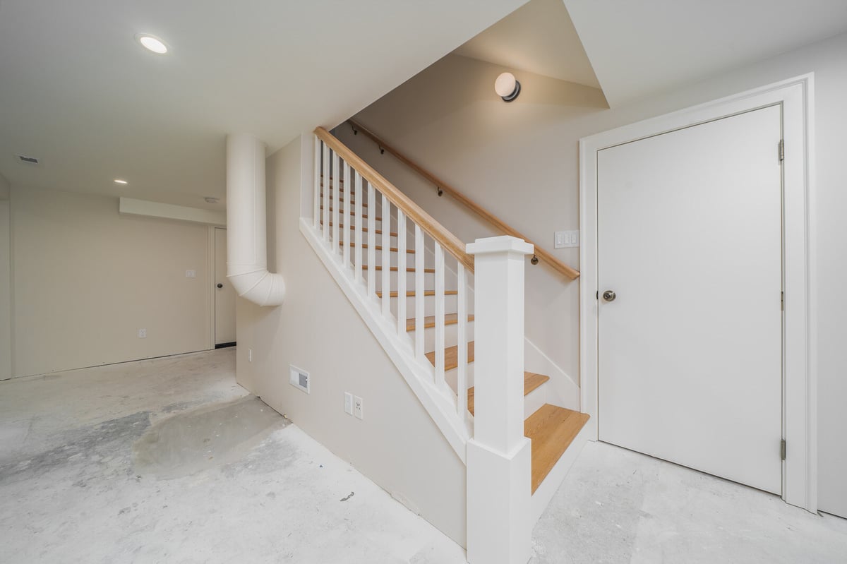 Modern basement stairway with white railings and wood steps in a Seattle remodel by CB Construction