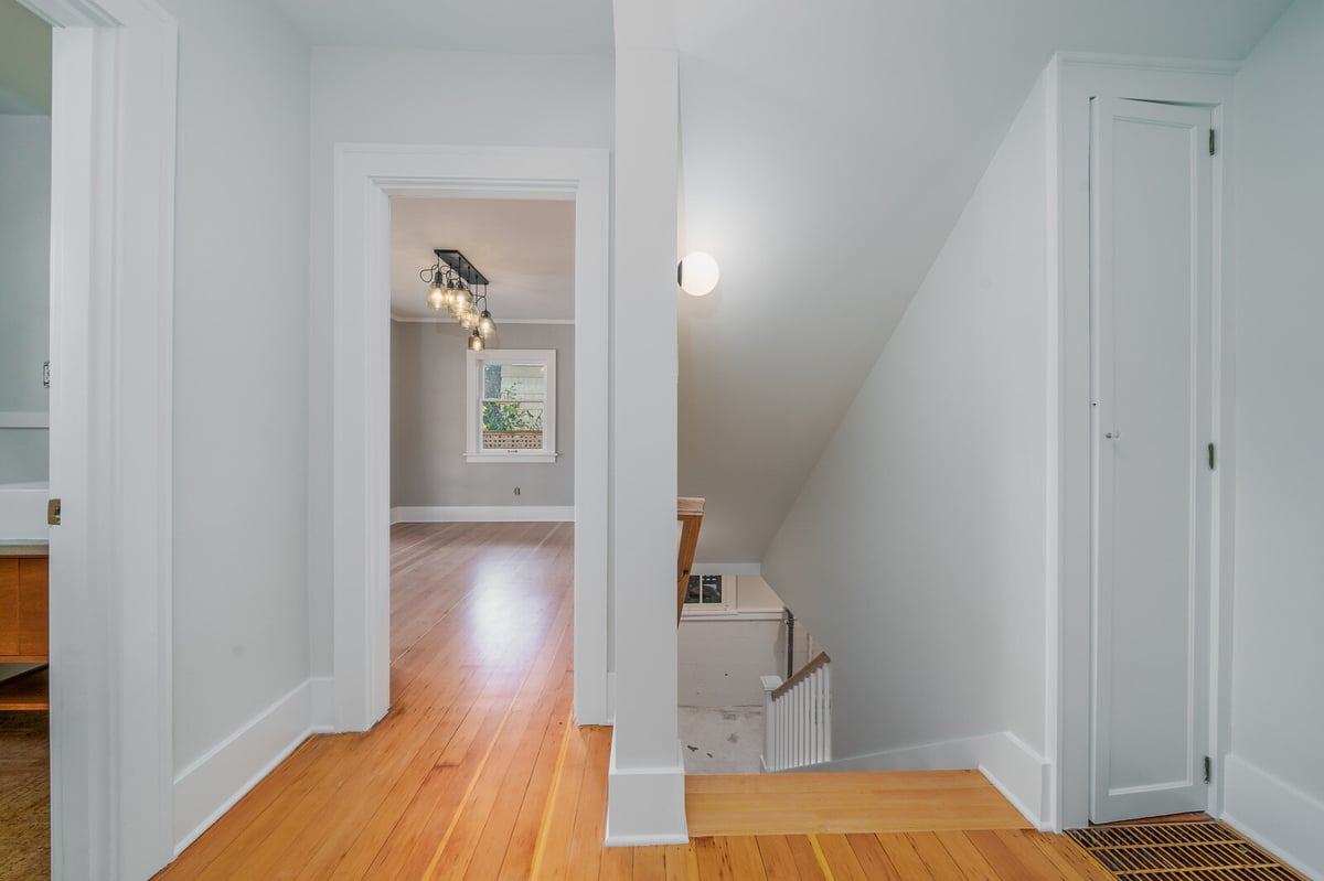 Open upstairs hallway with wooden floors and modern lighting by CB Construction in Seattle