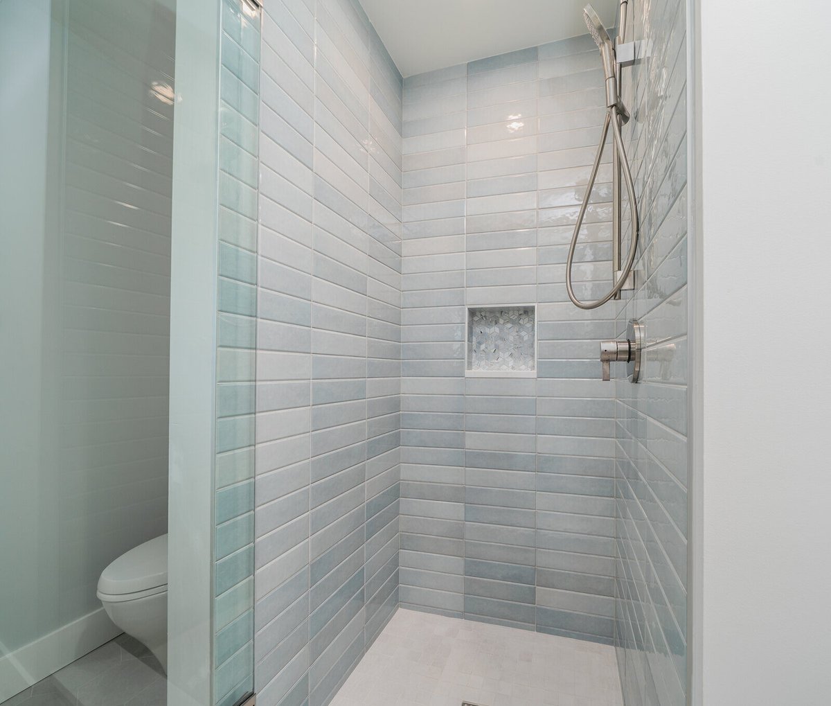 Walk-in shower with blue tiles and modern fixtures, part of a whole home remodel by CB Construction in Seattle