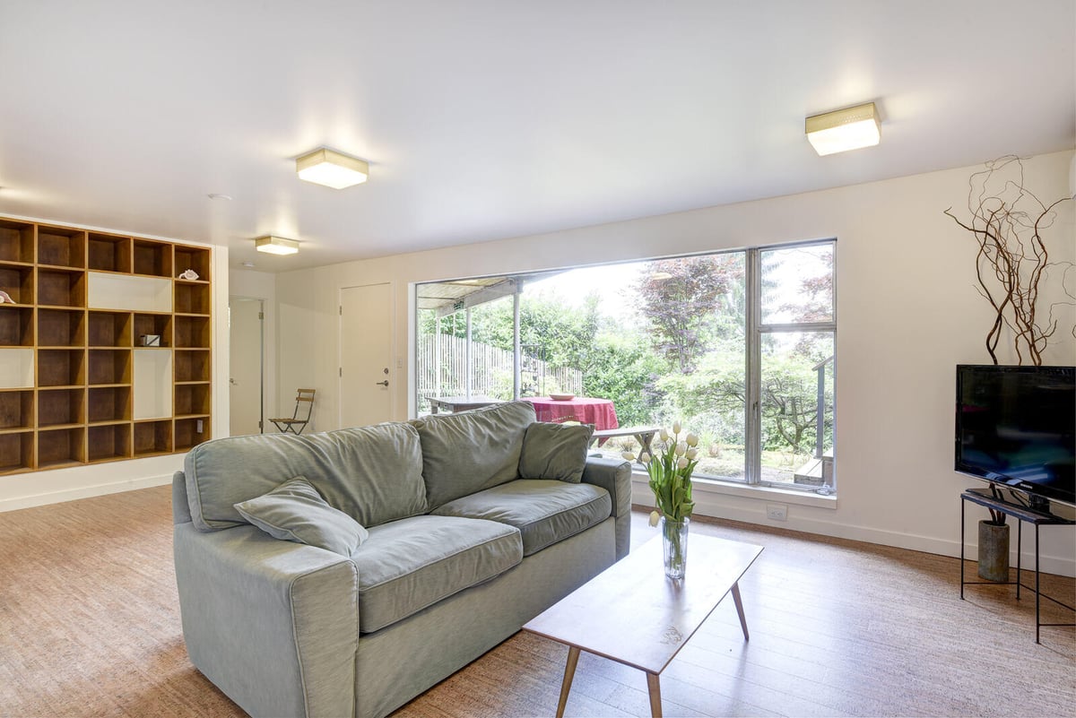 Comfortable living area with custom shelving and a garden view in a Seattle basement ADU, remodeled by CB Construction