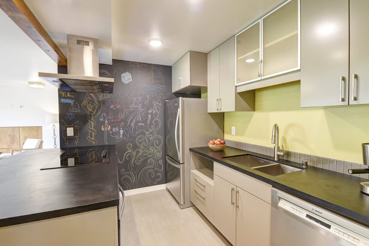 Kitchen area of a basement ADU in Seattle, featuring a chalkboard wall and stainless steel refrigerator, remodeled by CB Construction