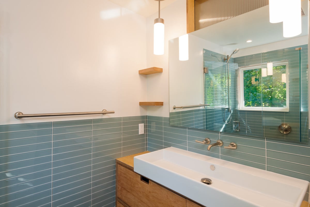 Bright bathroom with minimalist wood shelves and sleek fixtures, remodeled by CB Construction in Seattle