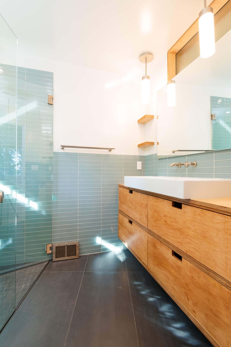 Contemporary bathroom design with wooden vanity and blue tiles, remodeled by CB Construction in Seattle