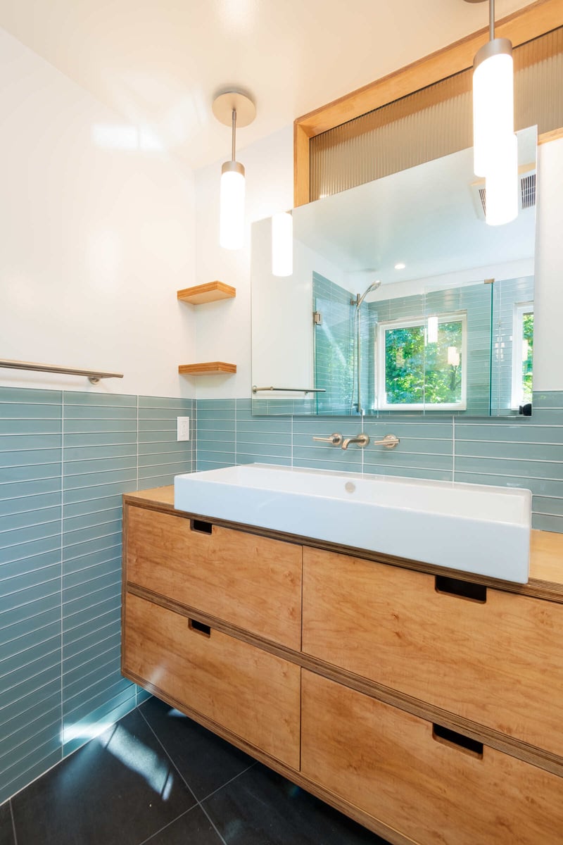 Contemporary bathroom with wood vanity and blue tile walls, remodeled by CB Construction in Seattle