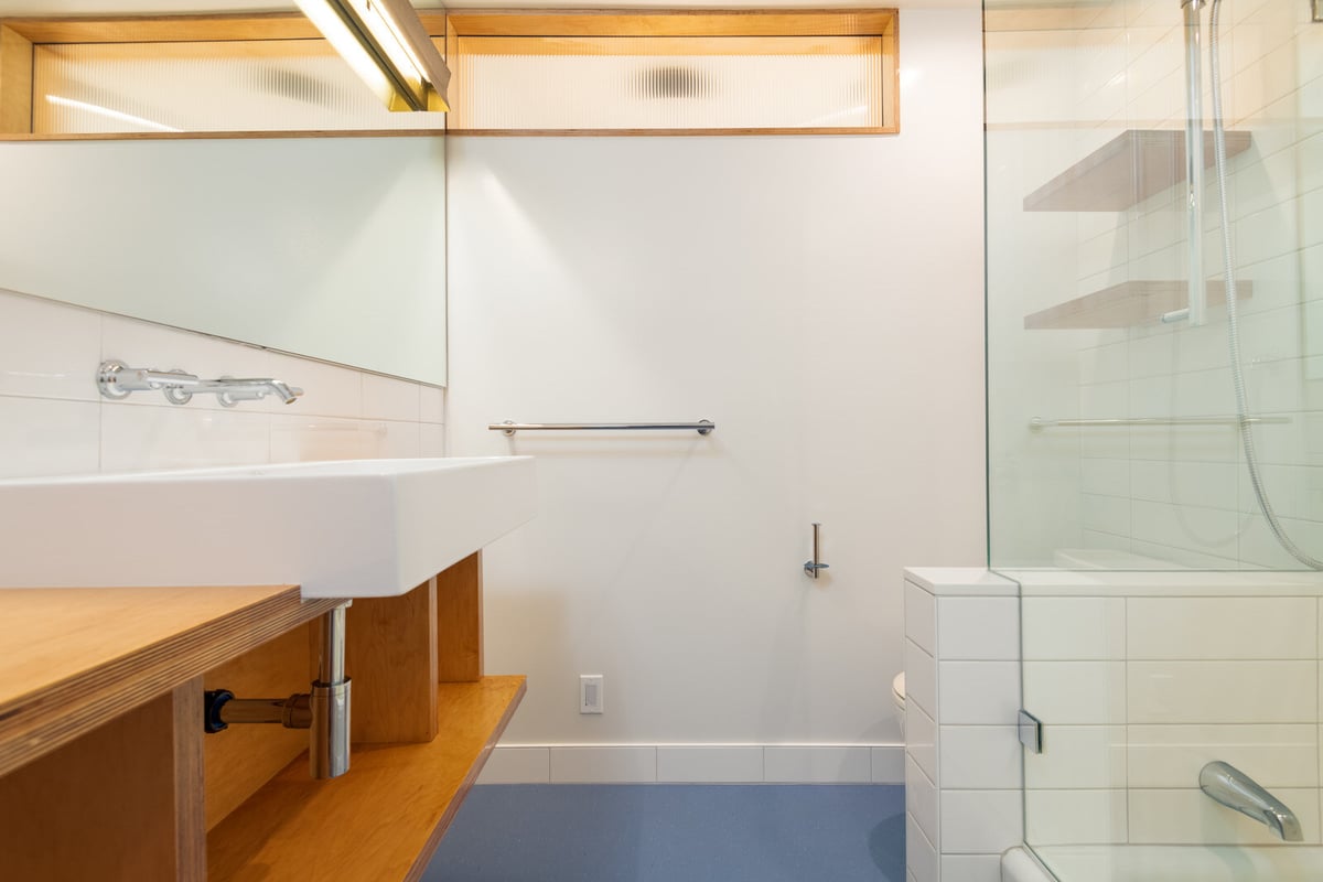 Main floor bathroom remodel by CB Construction in Seattle with minimalist design featuring a large rectangular sink and glass shower
