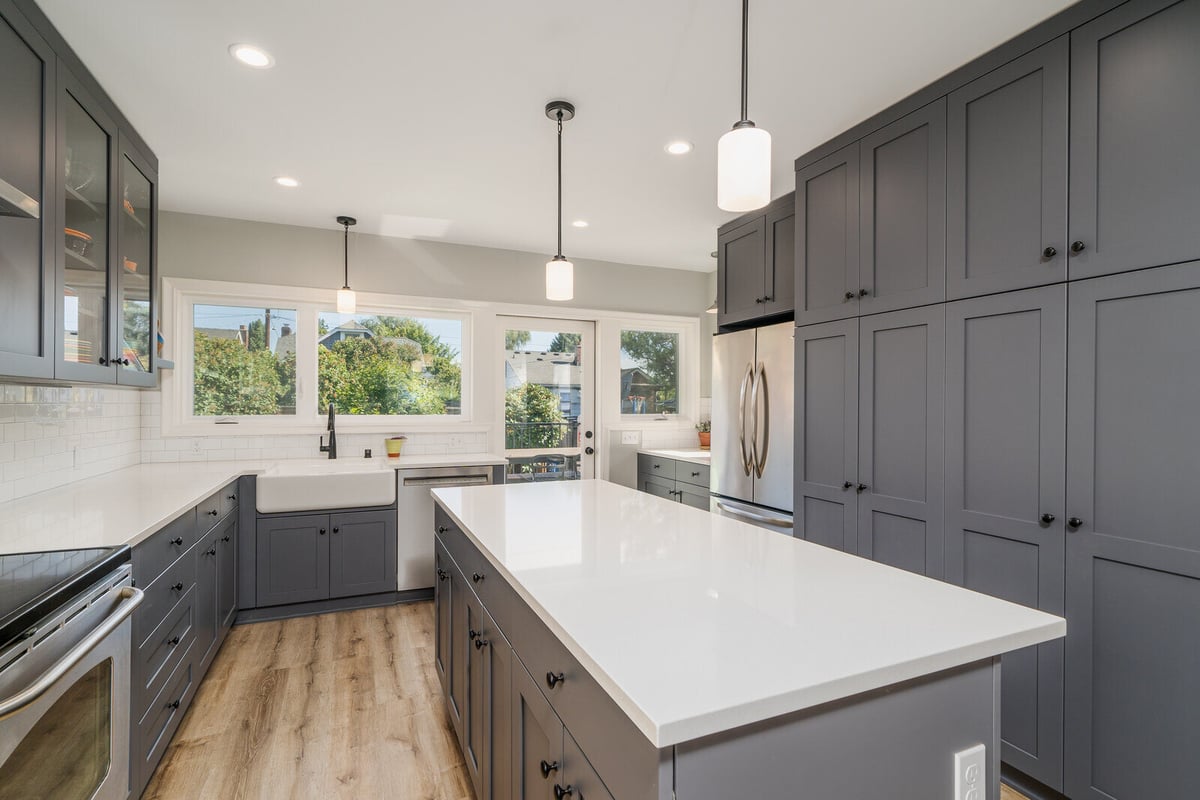 Bright kitchen in Seattle by CB Construction with a large island, white countertops, and grey cabinets