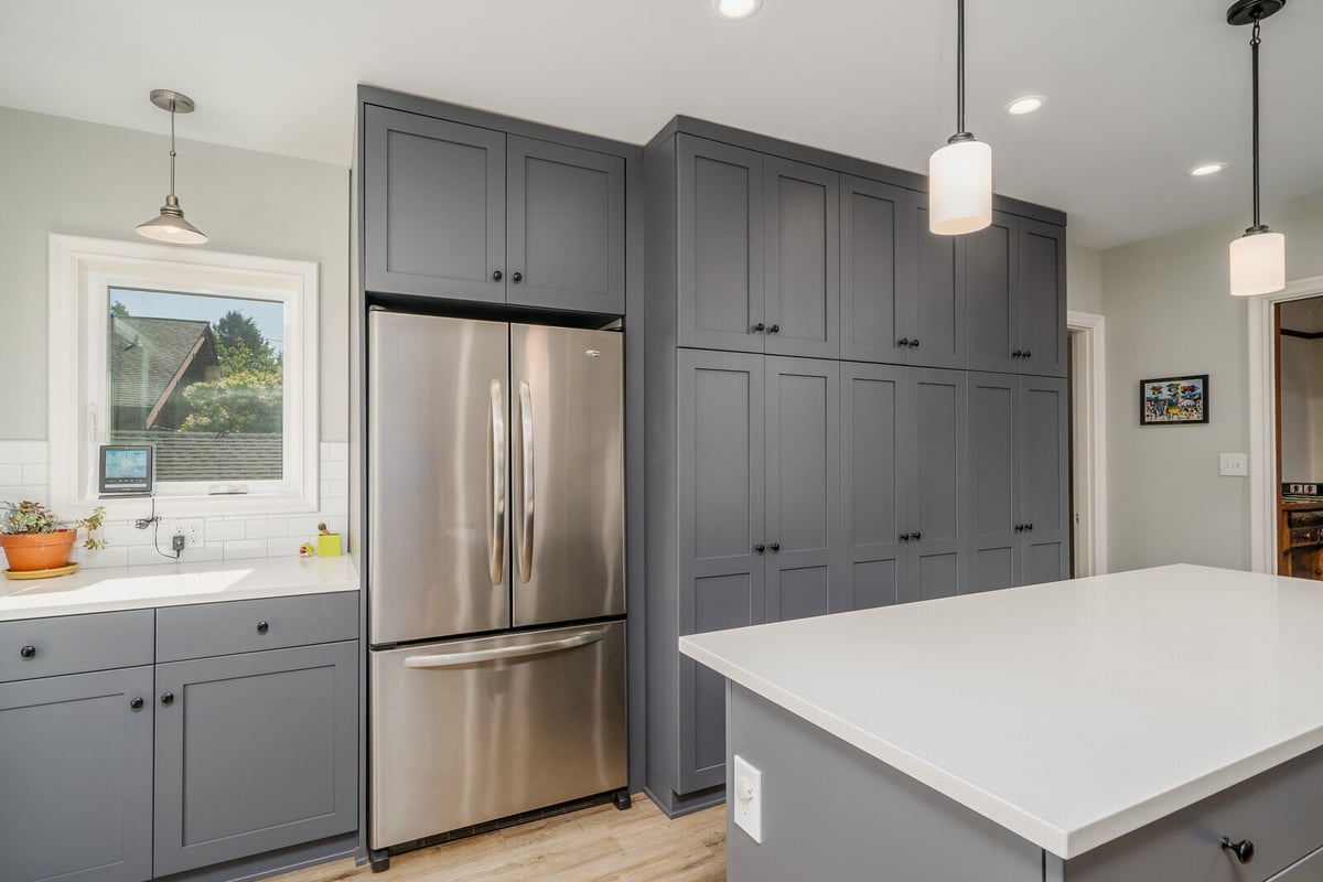 Kitchen remodel by CB Construction in Seattle with grey cabinetry, stainless steel fridge, and a spacious countertop