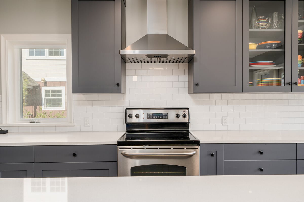 Seattle kitchen remodel by CB Construction with grey cabinets, stainless steel stove, and white subway tile backsplash