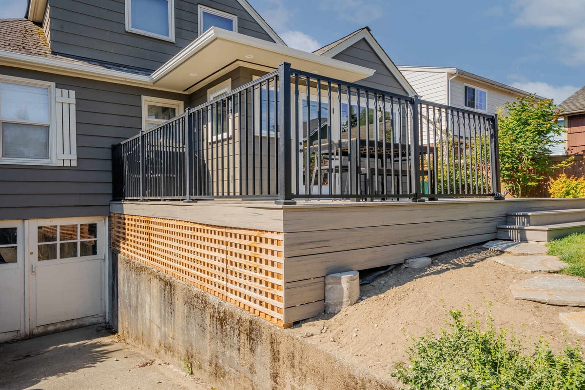 Side view of a Seattle home with a newly remodeled deck by CB Construction featuring railings and stairs