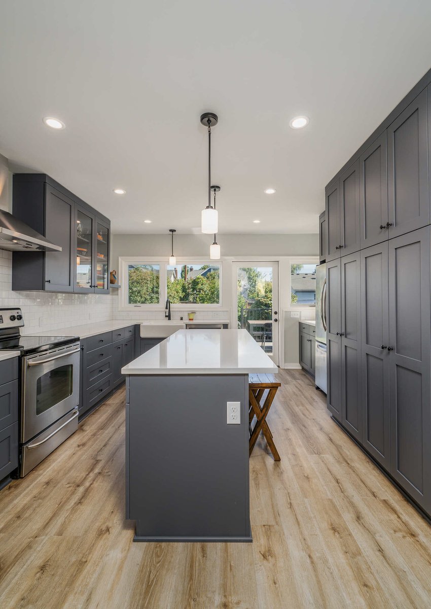 Spacious kitchen renovation by CB Construction in Seattle featuring grey cabinetry, a large island, and pendant lighting