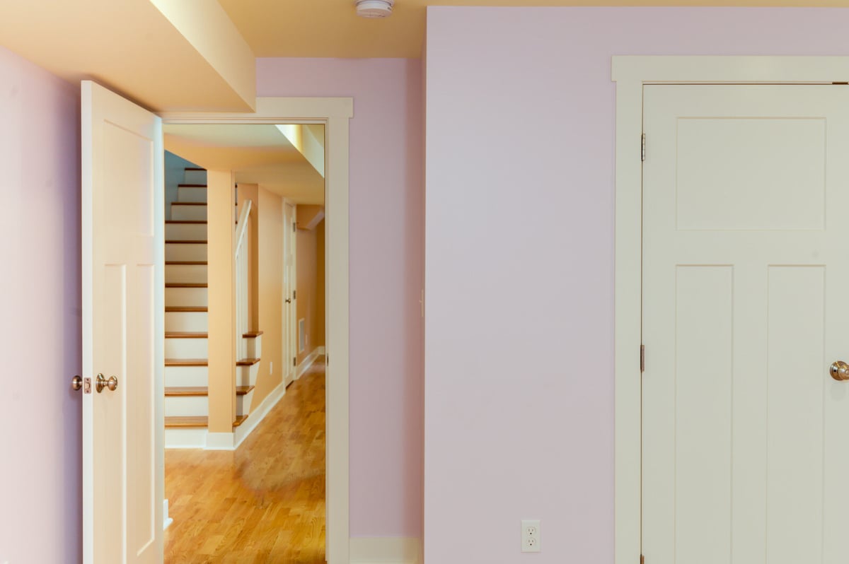 Basement hallway leading to remodeled rooms with light wood flooring in Seattle, by CB Construction