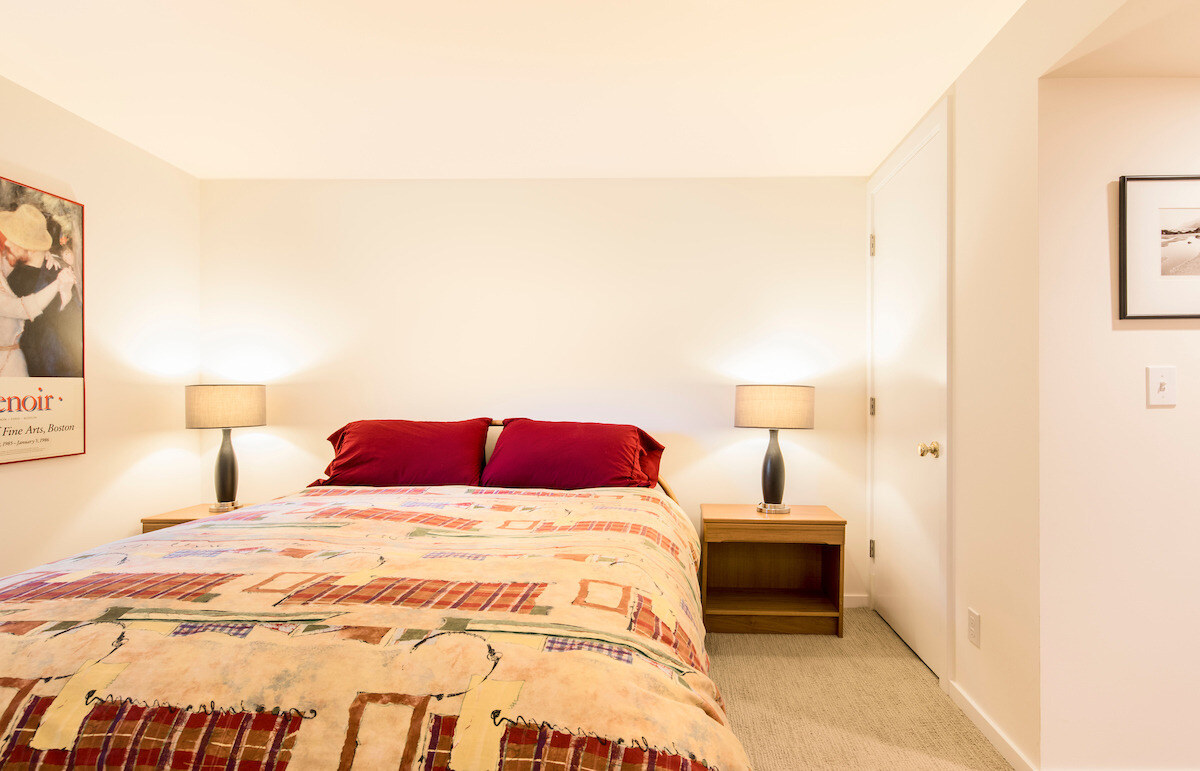 Simple and cozy bedroom in a remodeled Seattle basement Airbnb by CB Construction with modern lighting and artwork