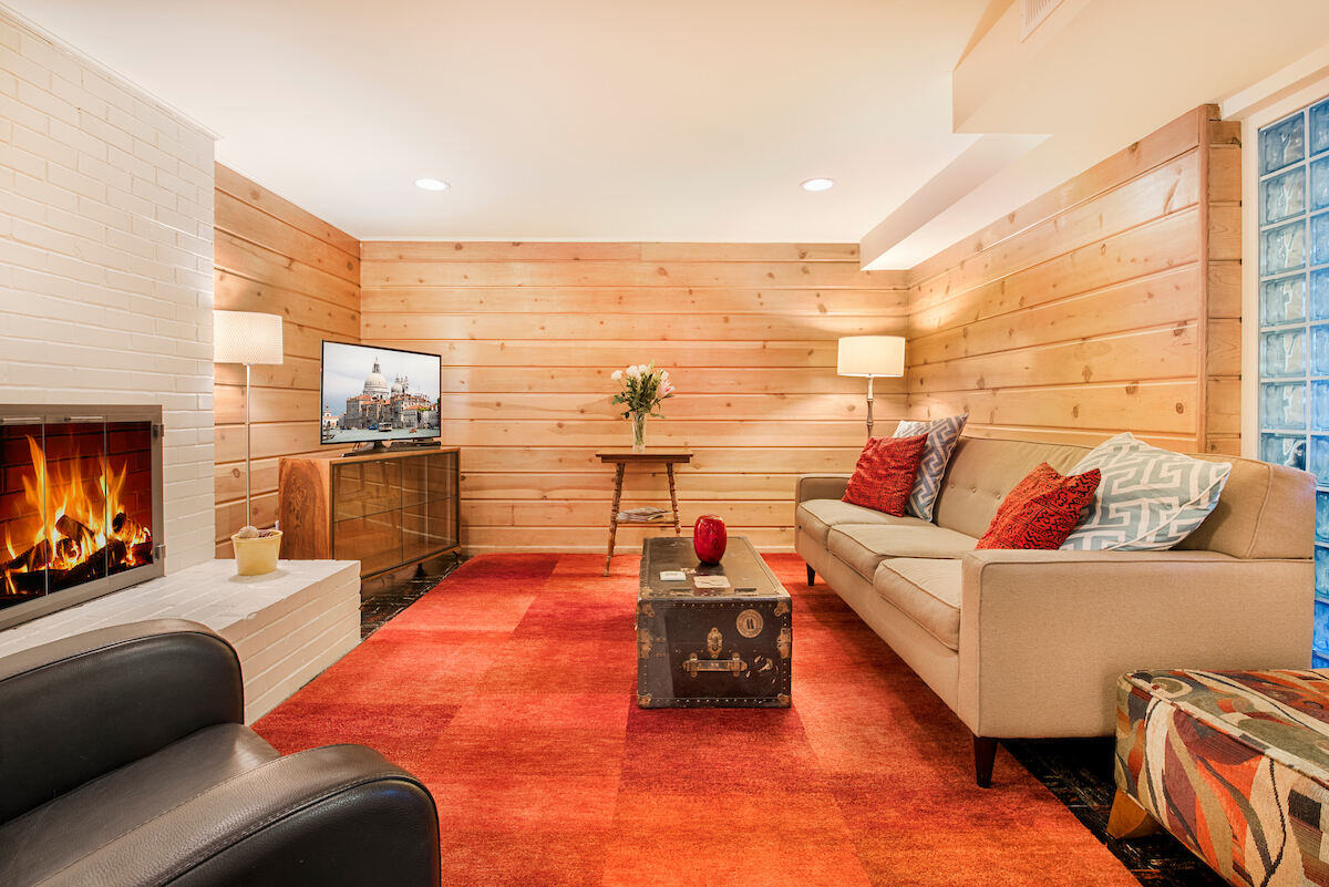 Warm and cozy living room in a remodeled Seattle basement Airbnb by CB Construction featuring a fireplace and wood-paneled walls