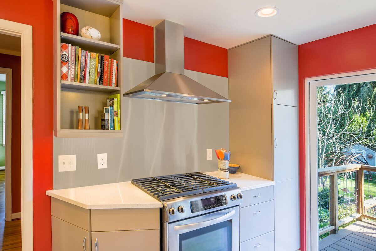 Modern kitchen with stainless steel range hood and red accent wall, renovated by CB Construction in Seattle