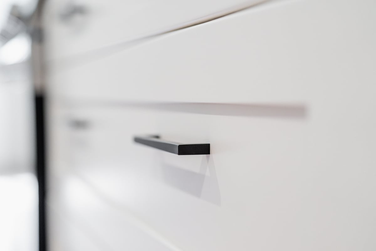 Close-up of sleek black cabinet handle on a white drawer in a Seattle ADU kitchen remodel by CB Construction