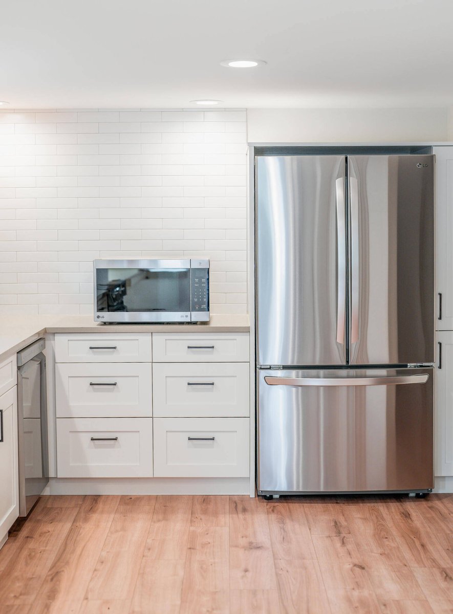 Stainless steel refrigerator and microwave in a bright Seattle ADU kitchen by CB Construction