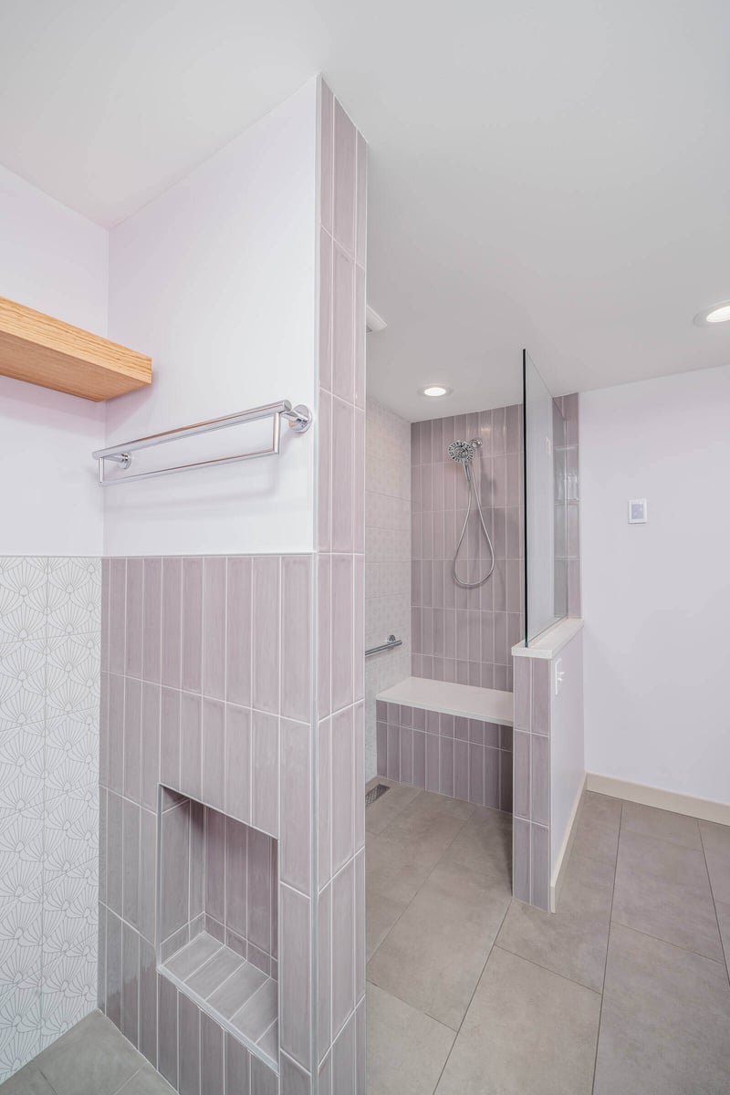 Tiled shower with built-in niche and glass divider, part of a Seattle basement ADU remodel by CB Construction