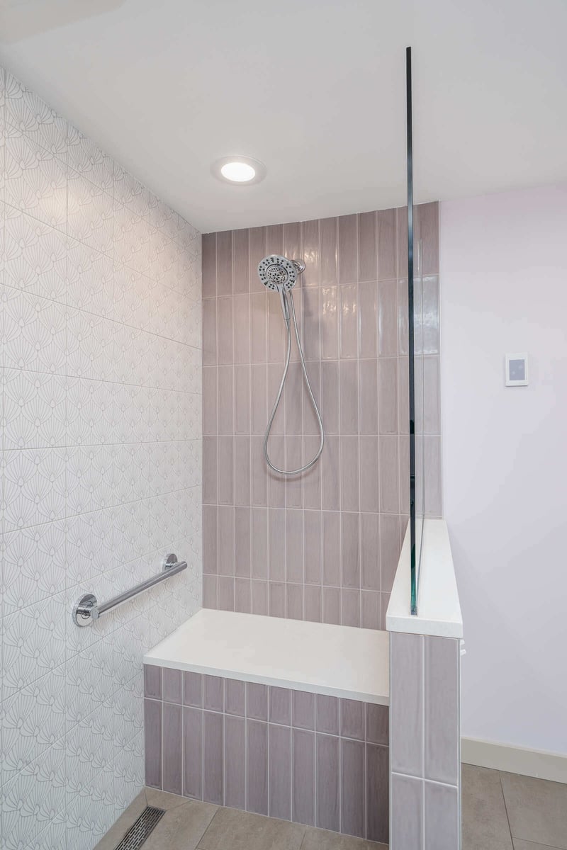 Tiled shower with handheld showerhead and bench, part of a basement ADU remodel by CB Construction in Seattle