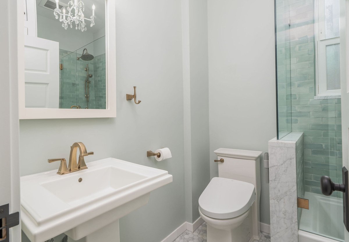 Bathroom shower remodel with green tile and brass fixtures in Seattle by CB Construction