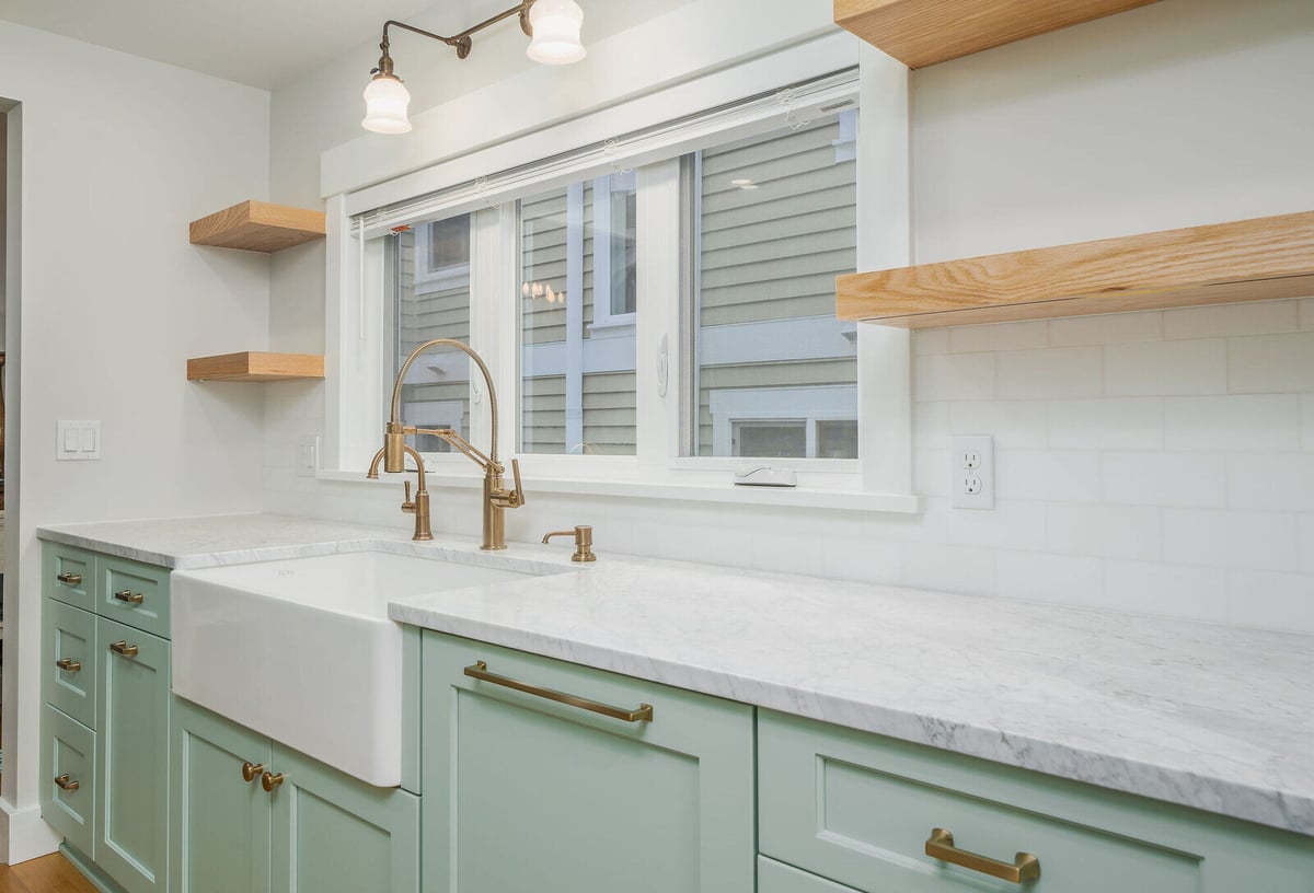 Bright and open kitchen design with marble counters and brass fixtures in Seattle by CB Construction