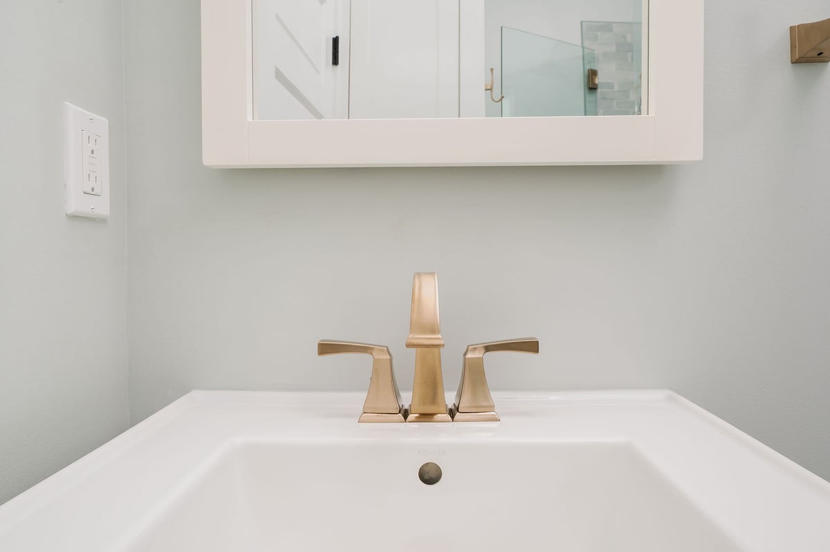 Close-up of a bathroom sink with a brushed gold faucet in a remodeled bathroom by CB Construction, Seattle