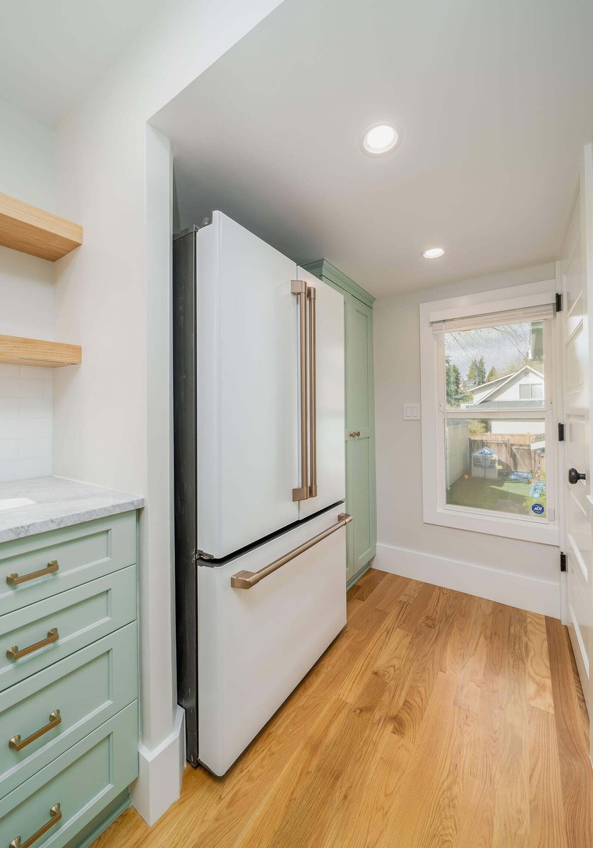 Close-up of brass drawer handles on mint green cabinetry in a Seattle kitchen remodel by CB Construction