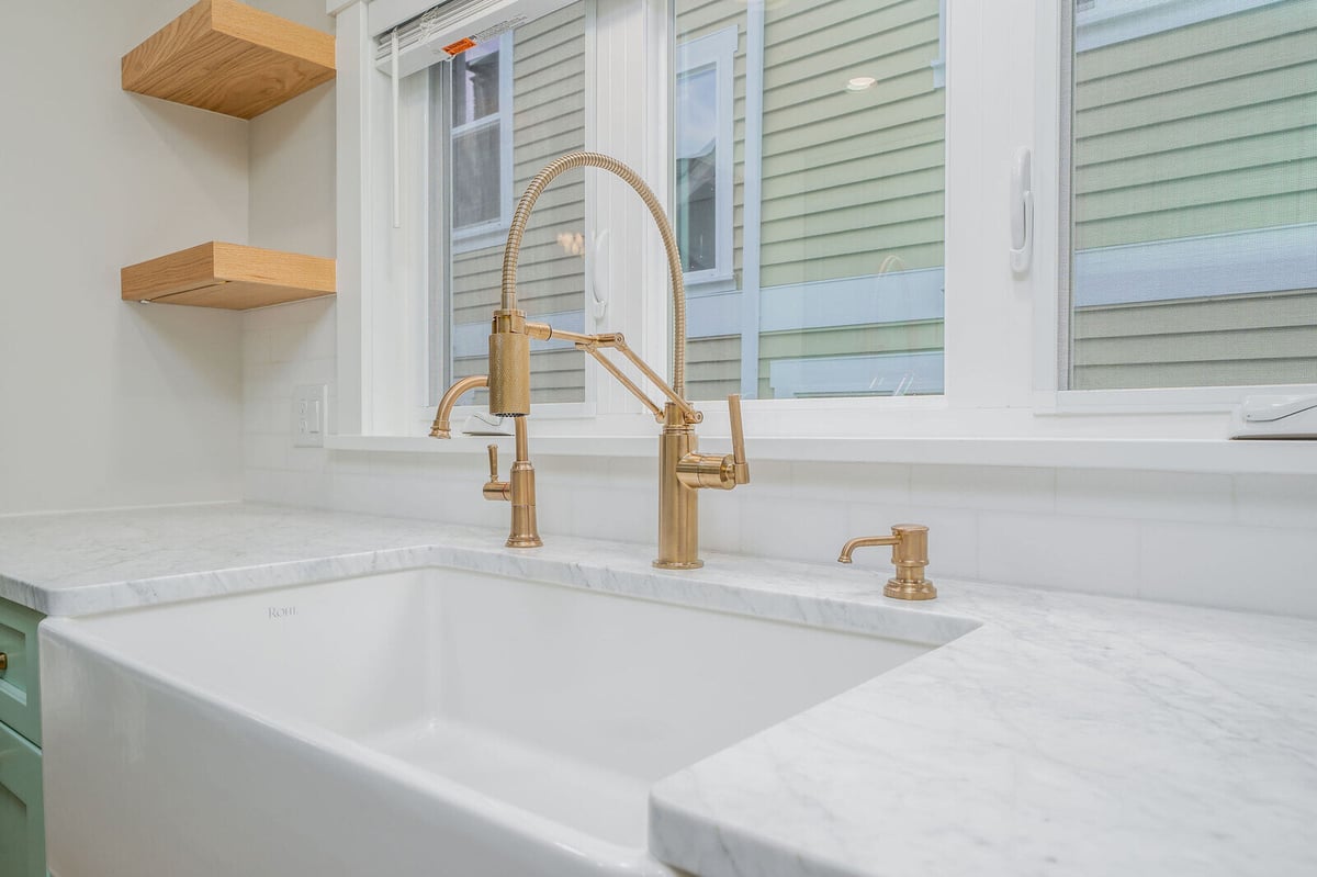 Close-up of farmhouse sink with brass fixtures in a Seattle kitchen by CB Construction
