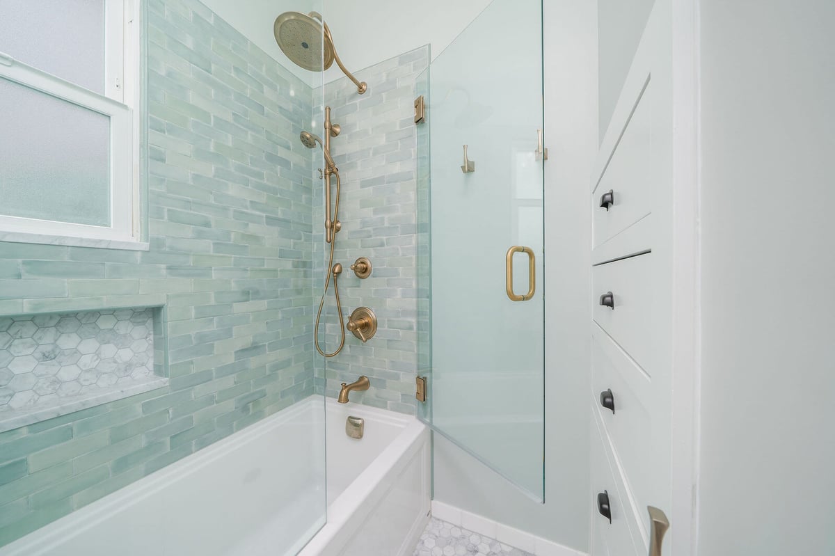 Elegant bathroom renovation with green tile and brass fixtures in Seattle by CB Construction