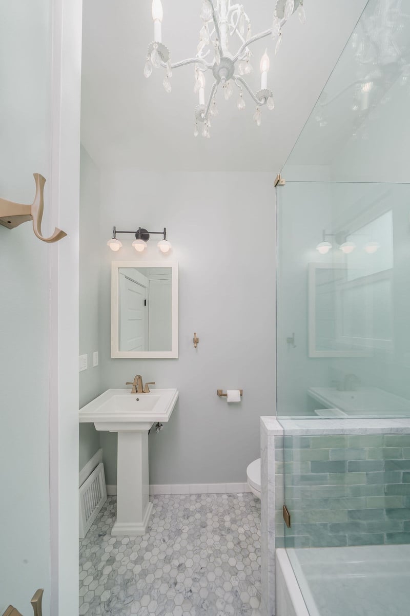 Glass shower door with brass handles and green tile in a bathroom remodel by CB Construction in Seattle