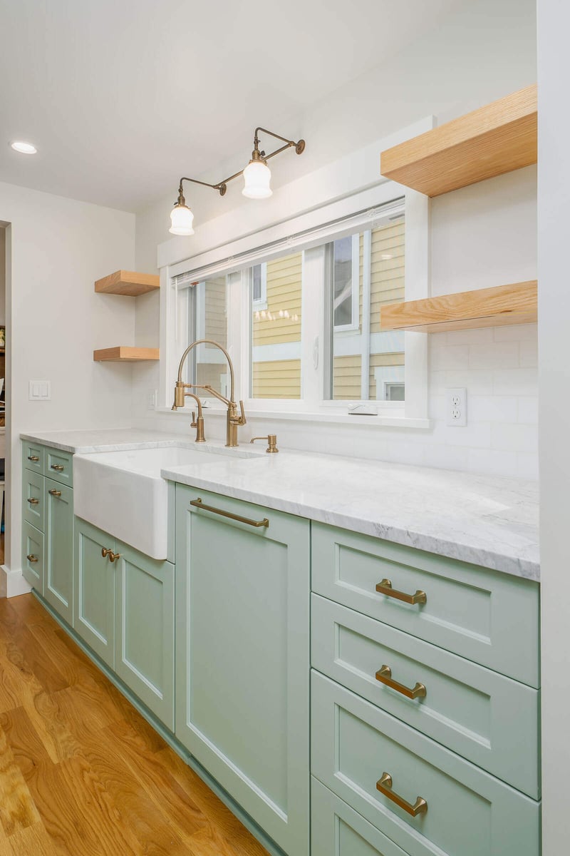 Mint green kitchen cabinets with brass hardware in a remodeled Seattle home by CB Construction