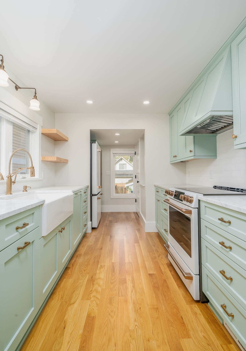 Spacious kitchen remodel with light green cabinets and hardwood floors in Seattle by CB Construction