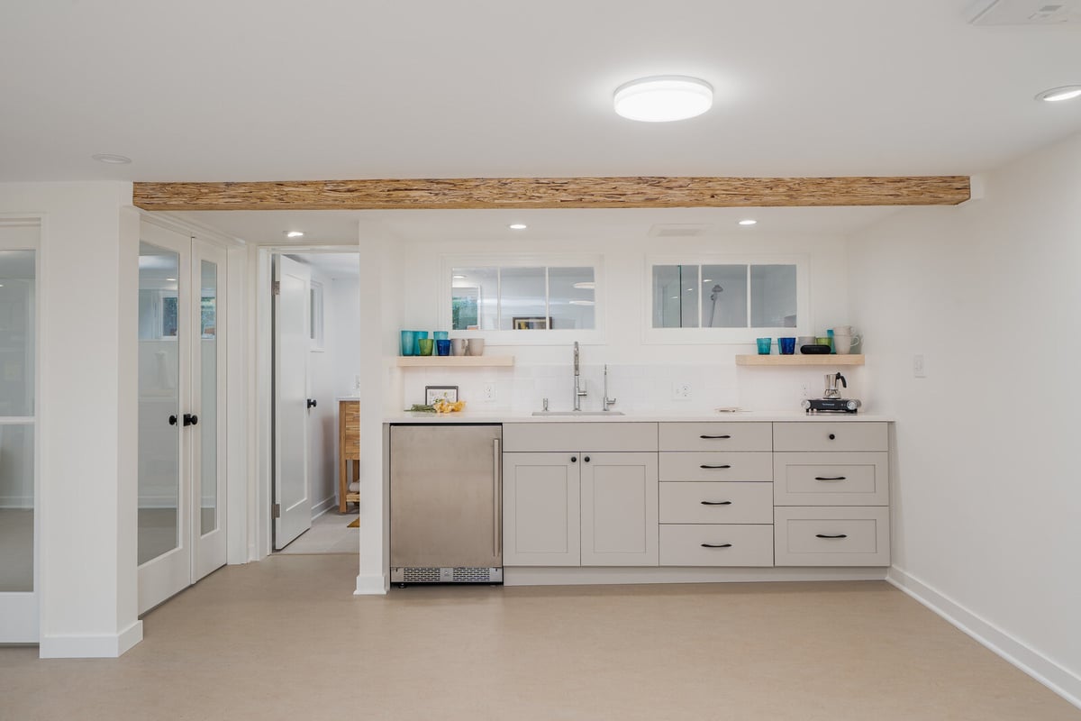 Basement kitchenette with modern white cabinetry and open shelving by CB Construction, Seattle