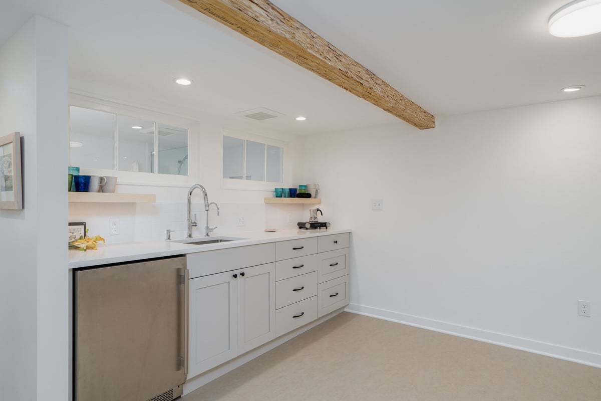 Basement kitchenette with sleek white design in a Seattle home remodel by CB Construction