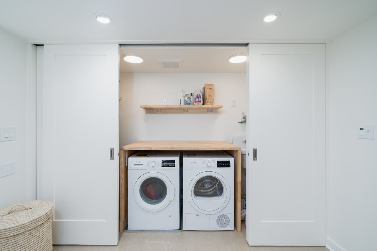 Bright laundry area in a Seattle basement remodel by CB Construction, featuring a compact washer and dryer setup