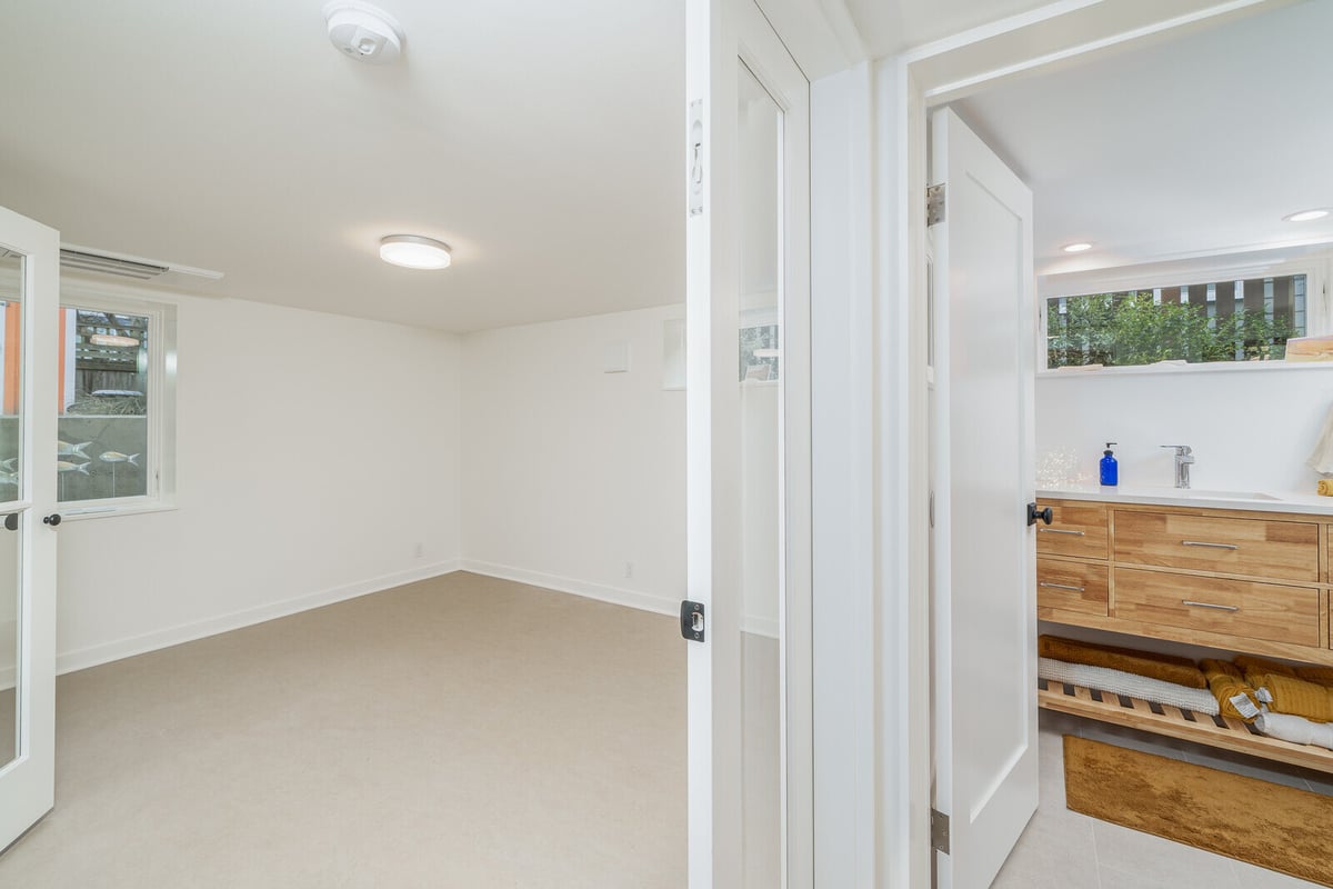 Bright, open basement with French doors leading to a bathroom in a Seattle remodel by CB Construction