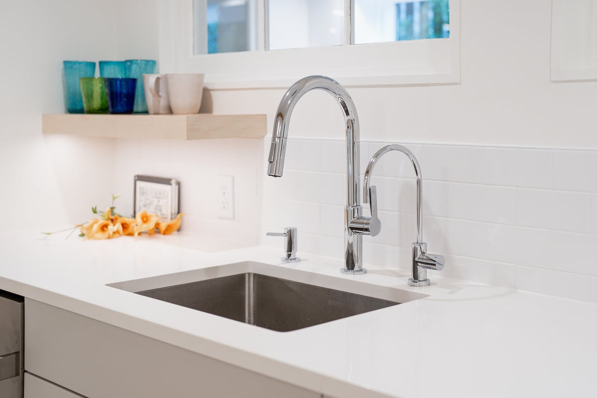 Close-up of modern sink and chrome faucet in a remodeled basement kitchenette by CB Construction, Seattle