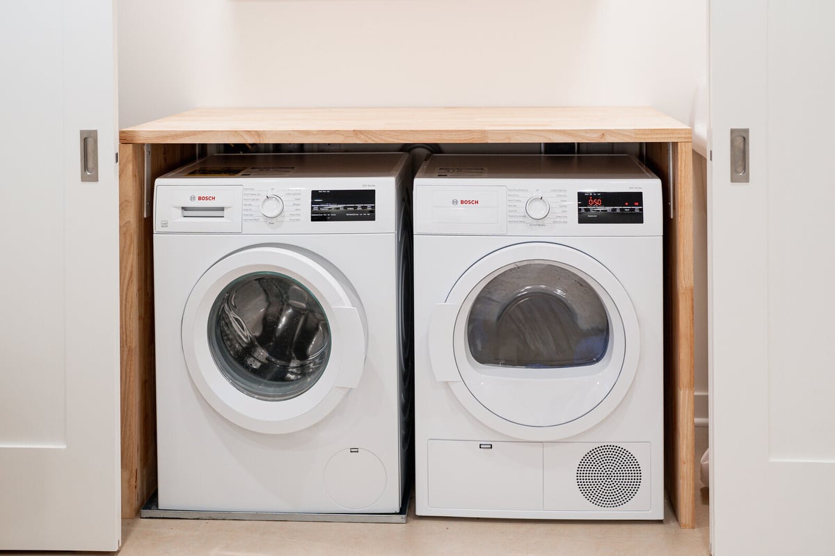 Compact laundry area with Bosch washer and dryer in a Seattle basement remodel by CB Construction