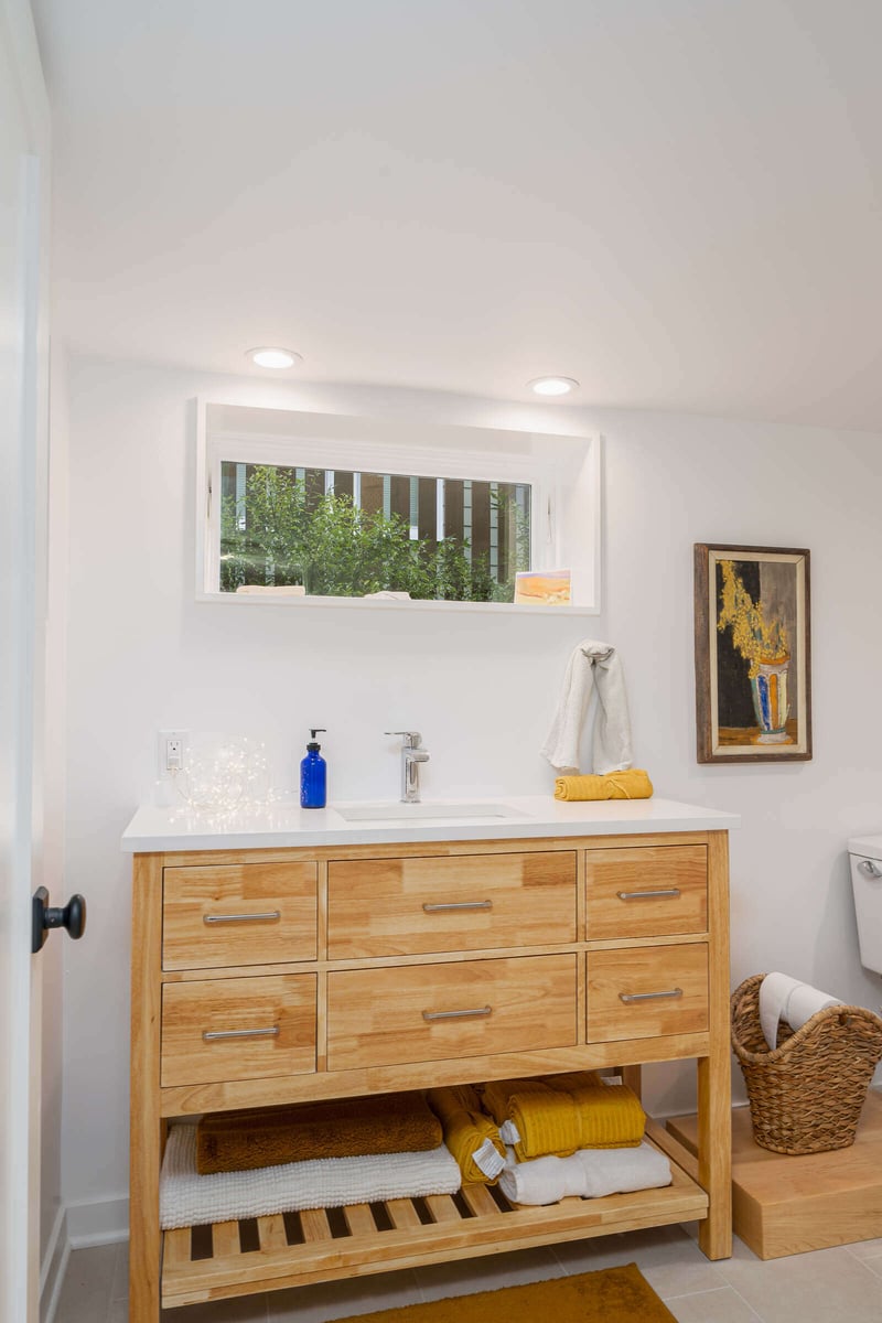 Elegant bathroom sink area in a Seattle basement remodel by CB Construction, with wooden cabinetry