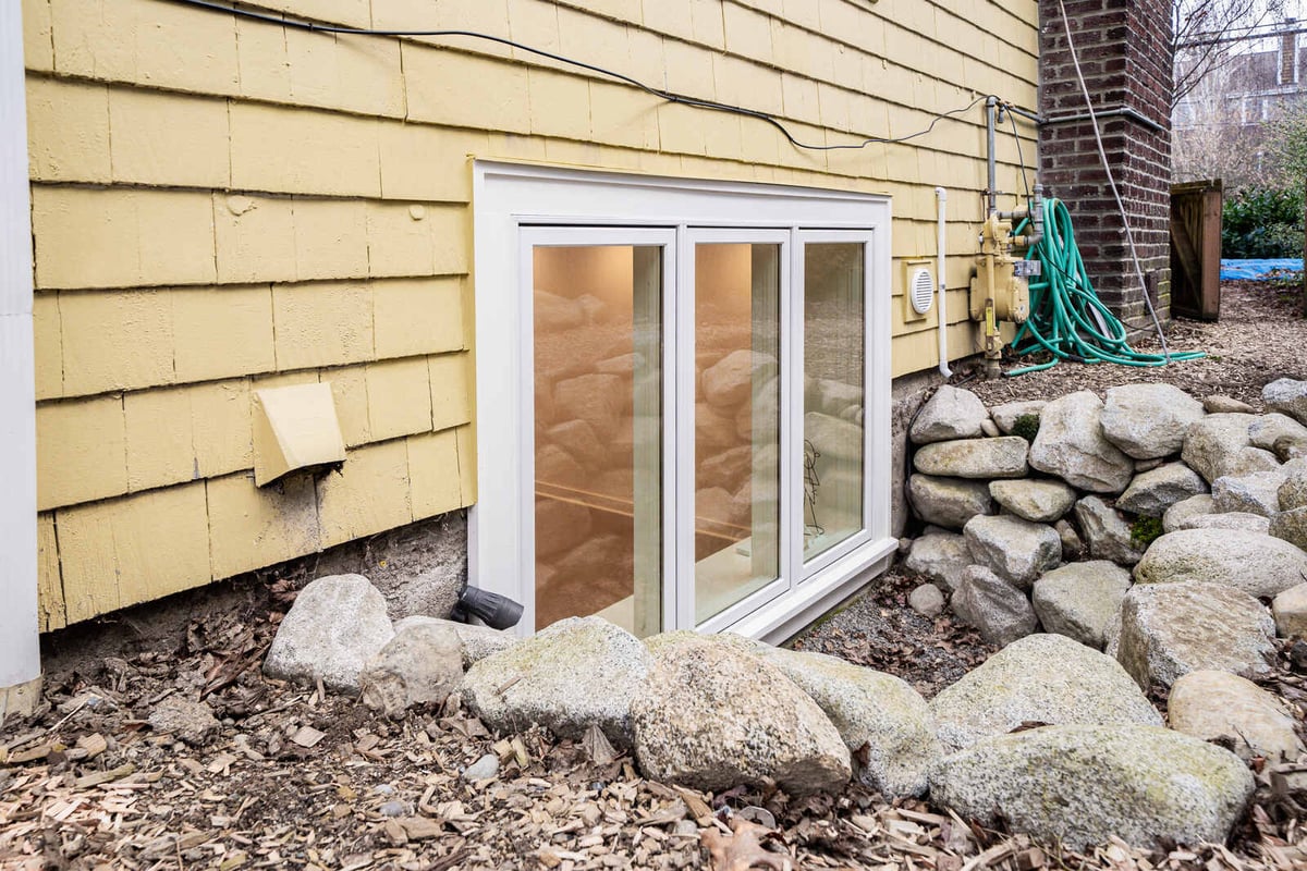 Exterior view of a basement window with stone landscaping in a Seattle home by CB Construction