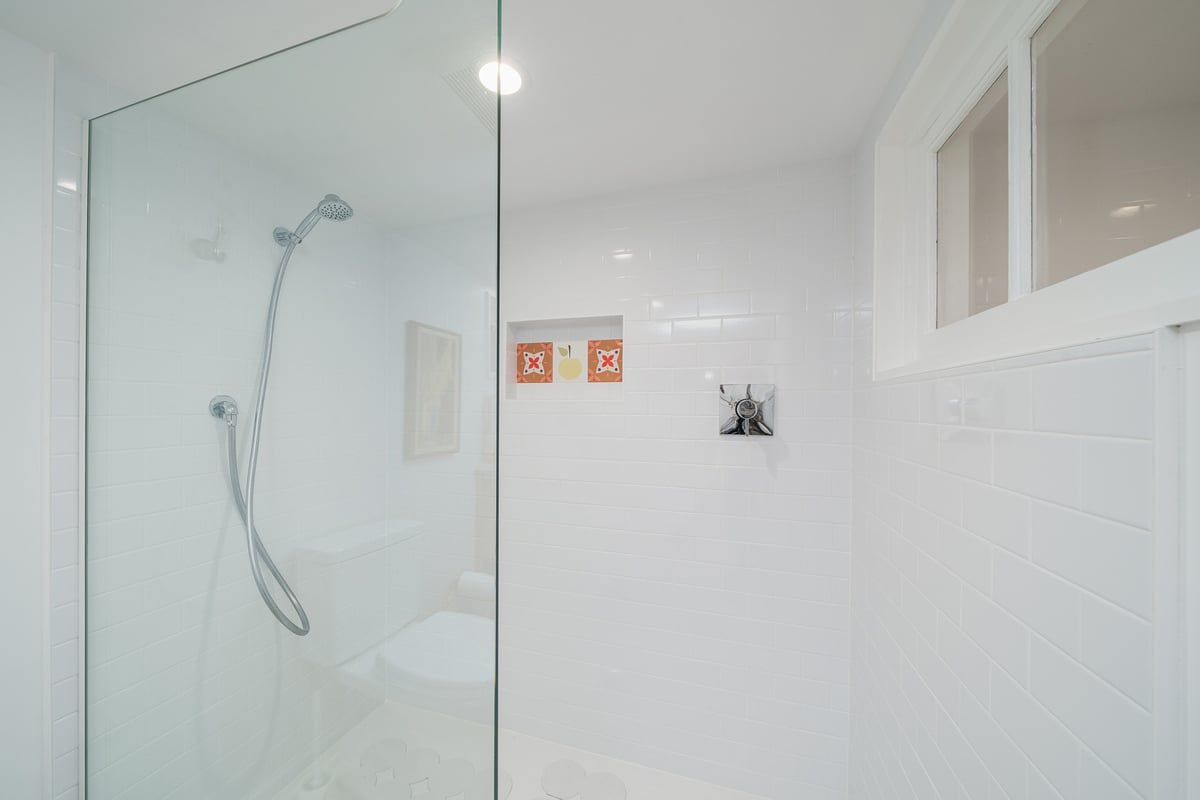 Glass shower in a Seattle basement bathroom remodel by CB Construction, featuring white subway tiles