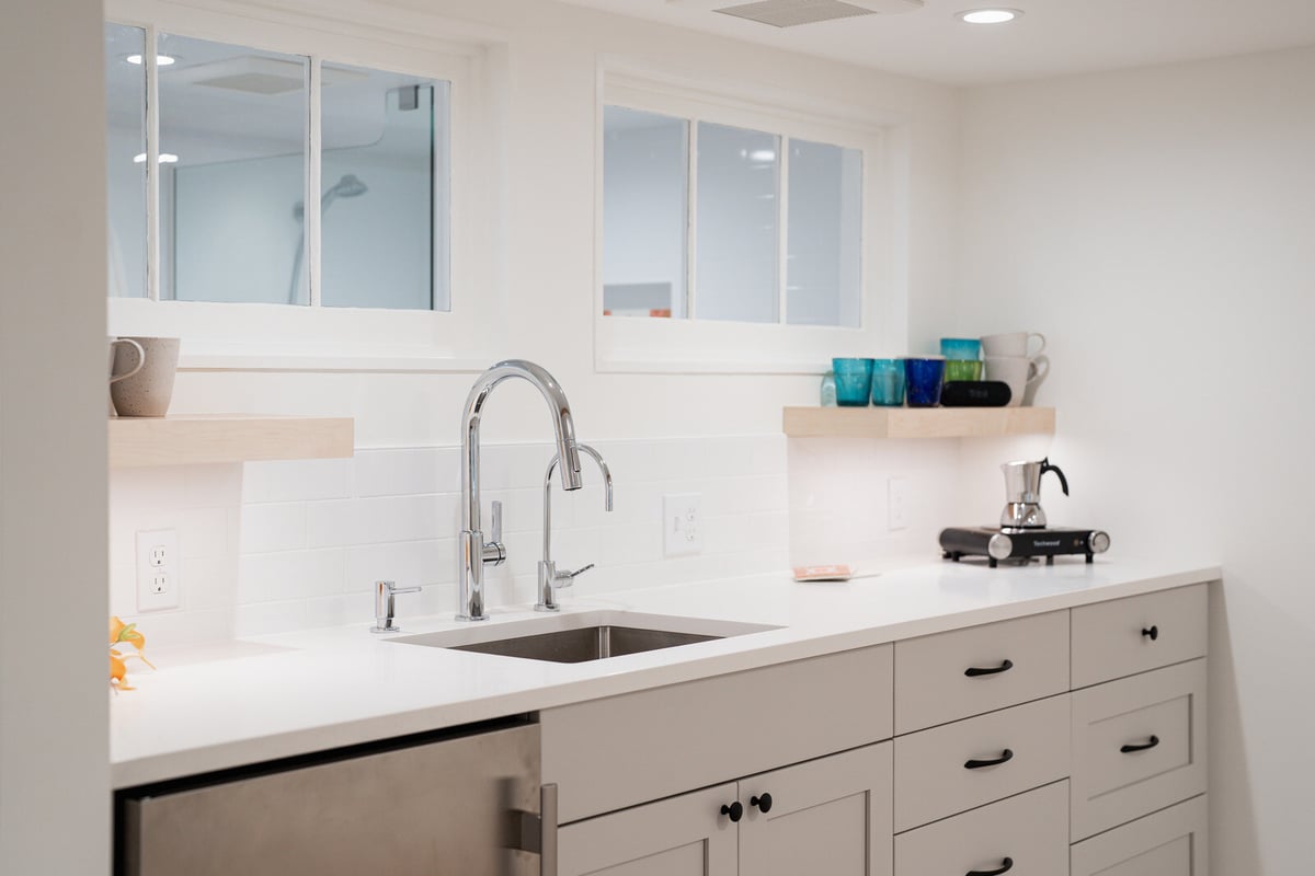 Modern basement kitchenette remodel with white cabinets and a chrome faucet by CB Construction in Seattle