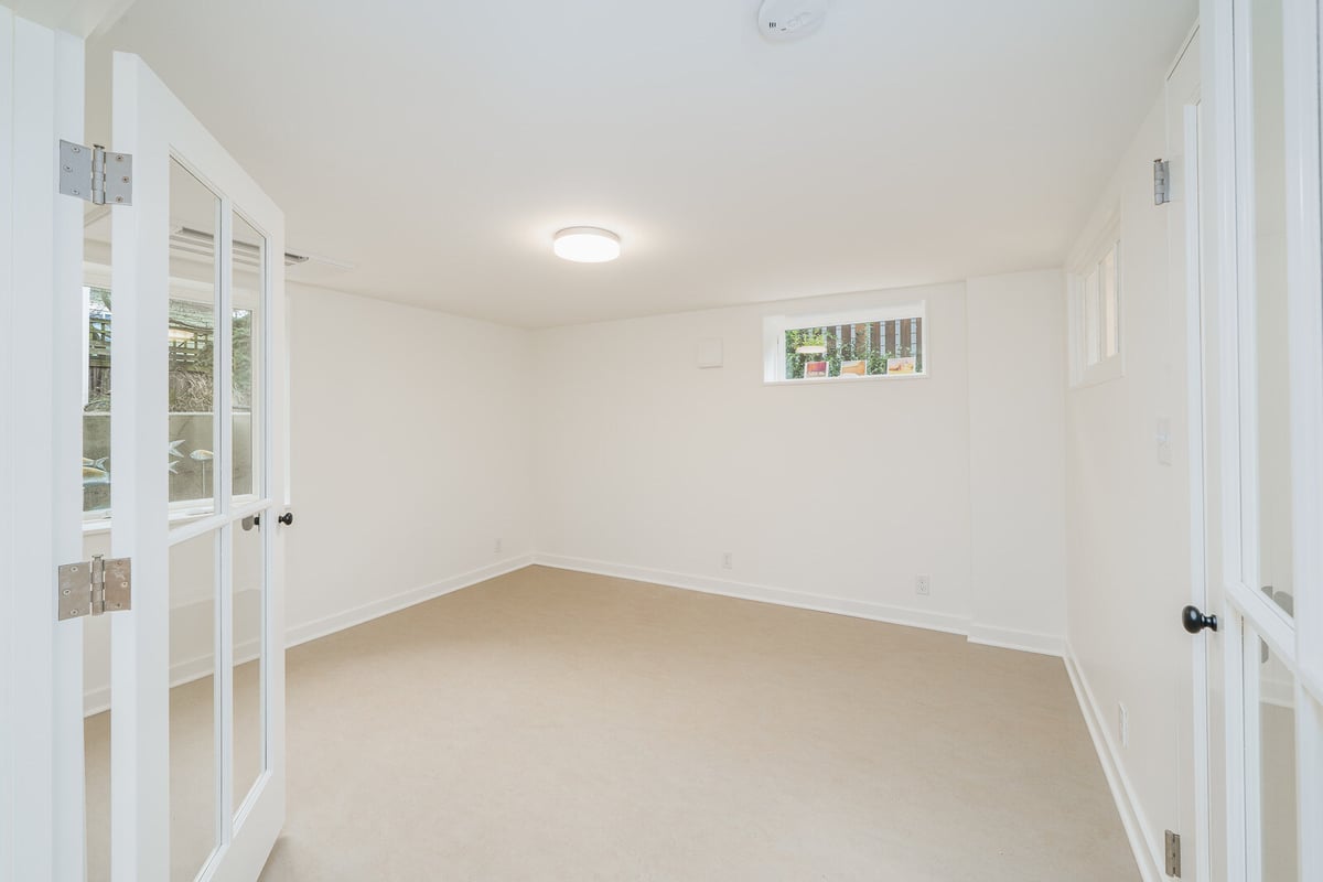 Modern, light-filled basement room with glass French doors in a Seattle remodel by CB Construction