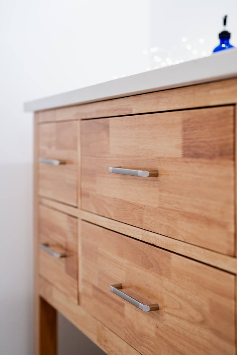 Natural wood vanity with brushed metal handles in a Seattle basement remodel by CB Construction